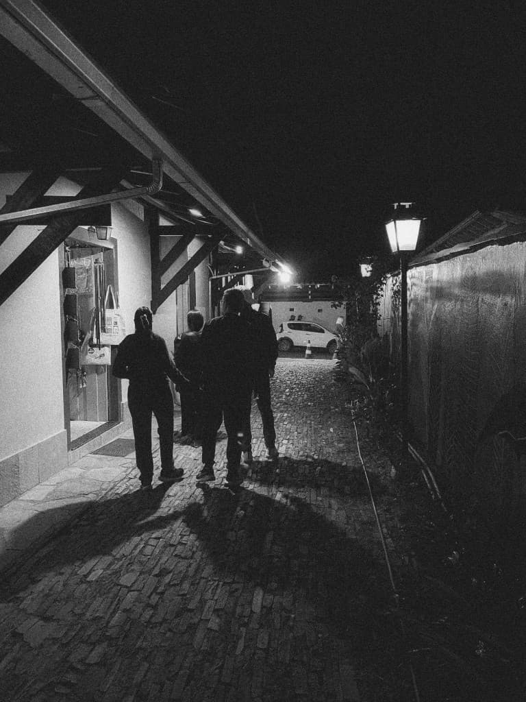 Beco de paralelepípedos à noite, três pessoas de costas