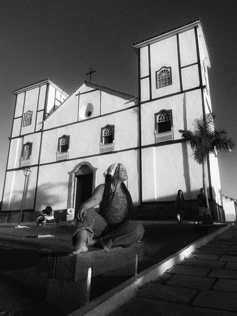 Mulher sentada num banco em frente a uma igreja